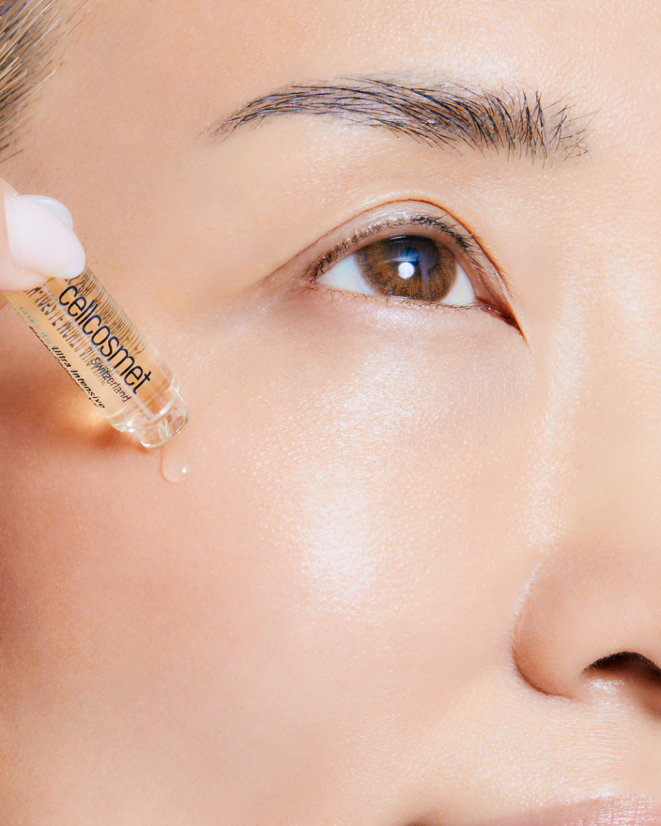 Close-up of a person applying a dropper of Cellcosmet serum to their eye.