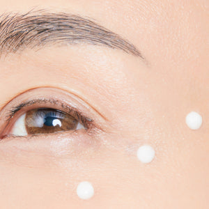 A close-up of a woman's eye area featuring with white dots, showcasing the application of Cellular Eye Contour Cream.