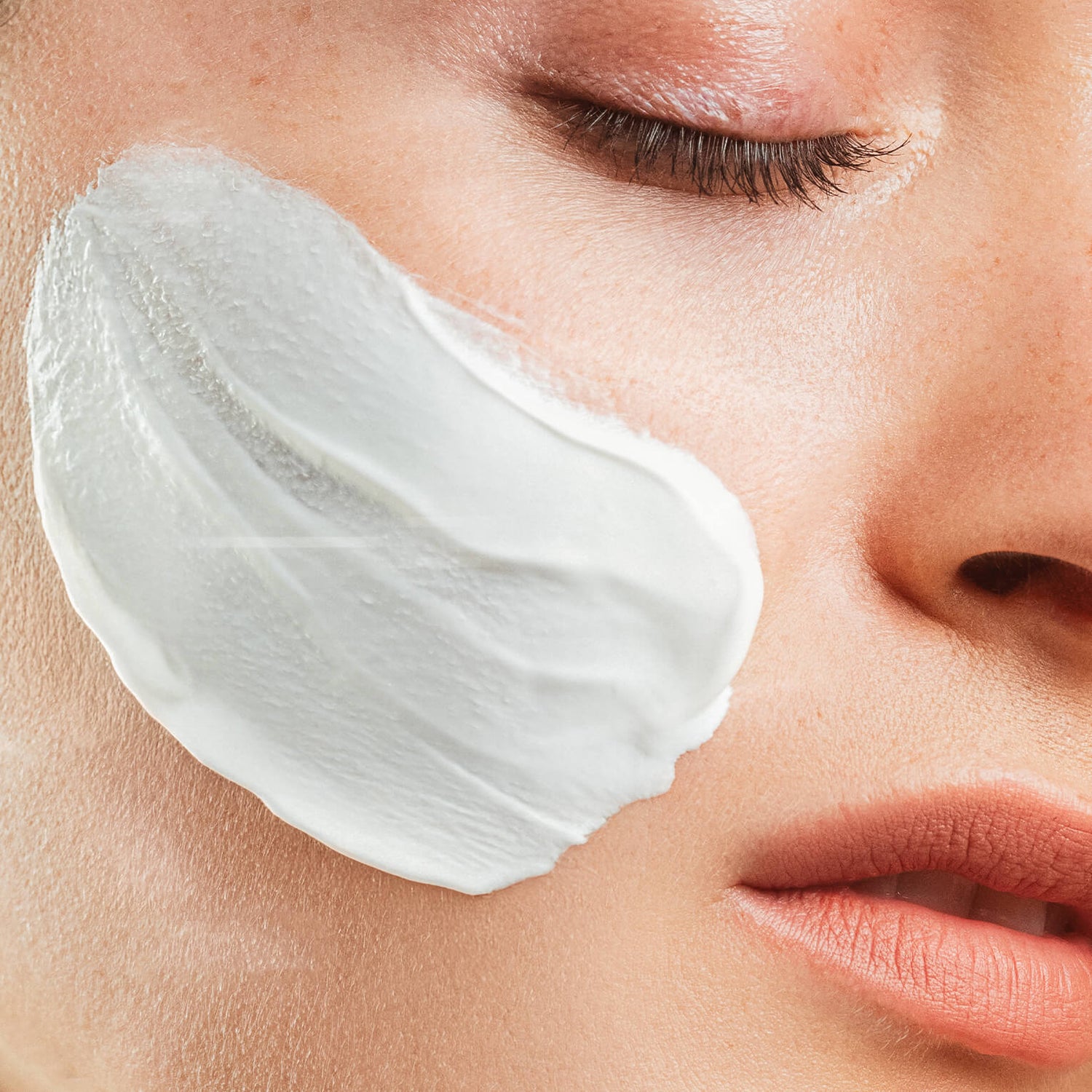 Close-up of a woman applying hydra soothing mask cream to her face