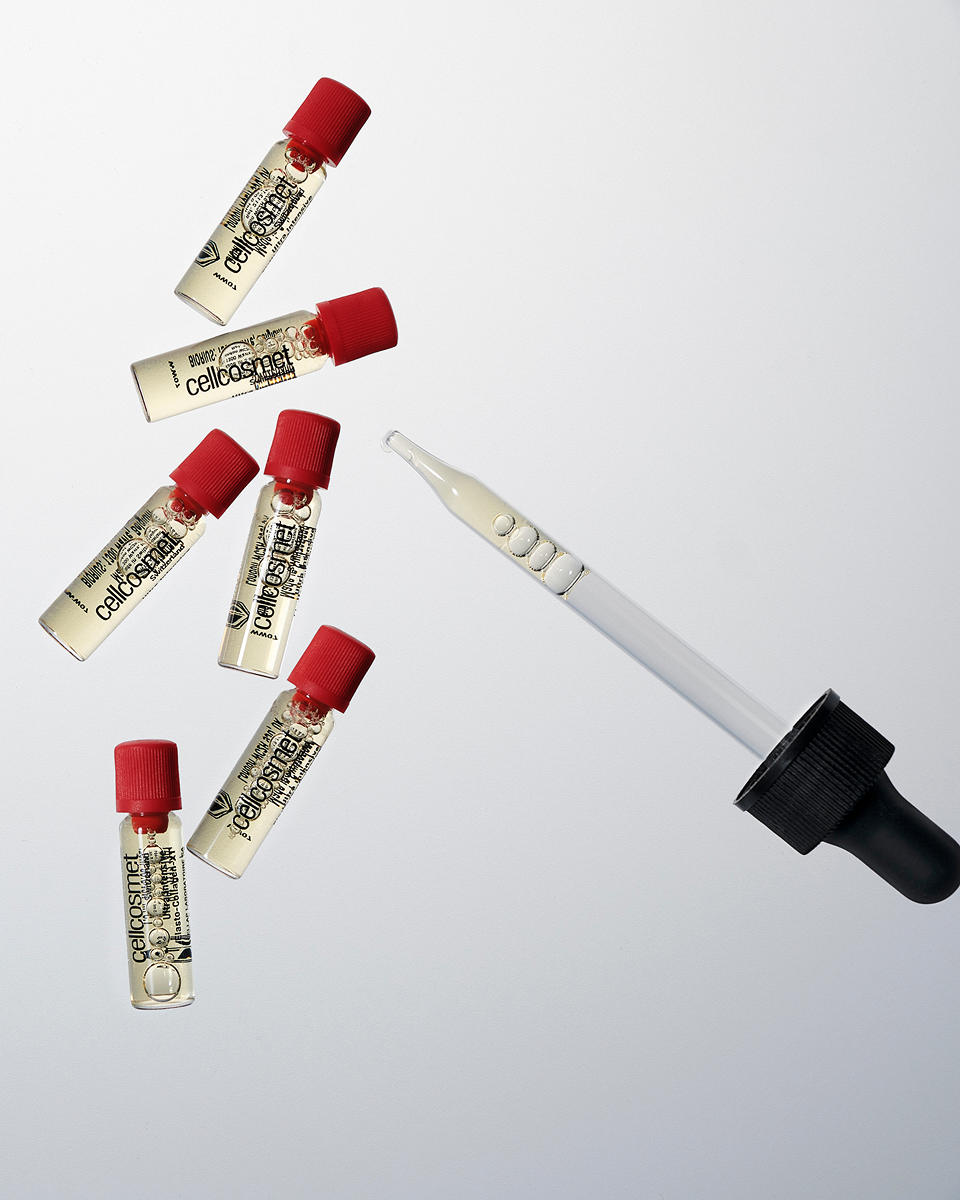 Set of small vials with red caps and a dropper on a light gray background