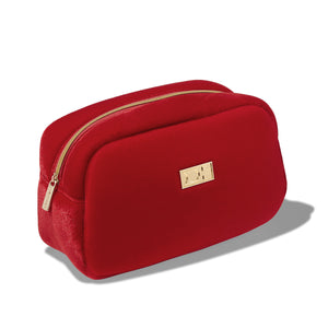 Red velvet toiletry bag with gold zipper and logo on a white background