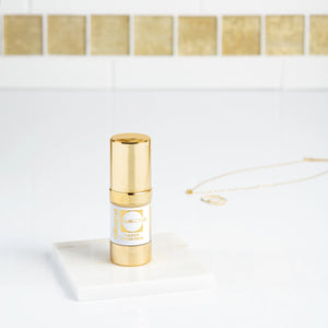 CellLift Eye Contour Cream, a gold and white bottle, displayed on a white marble countertop with jewelry in the backdrop.