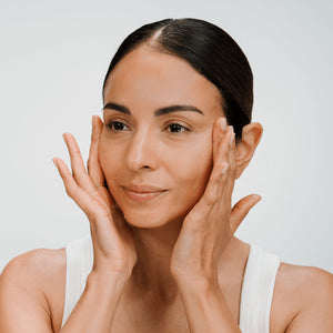 Woman applying cellLift Cream to her face with a neutral background