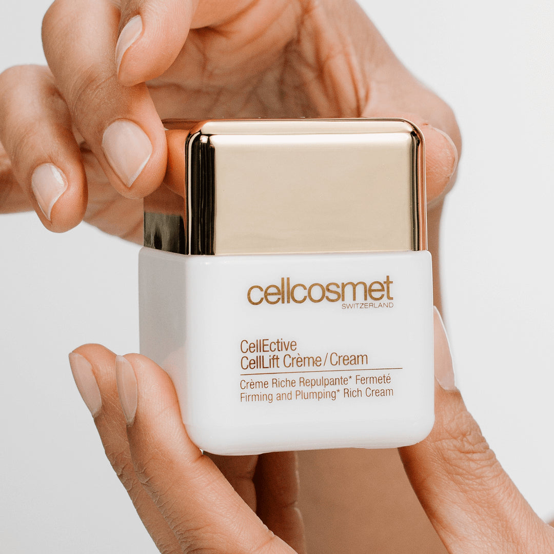 Hand holding a white and gold celllift cream container labeled 'cellcosmet'.