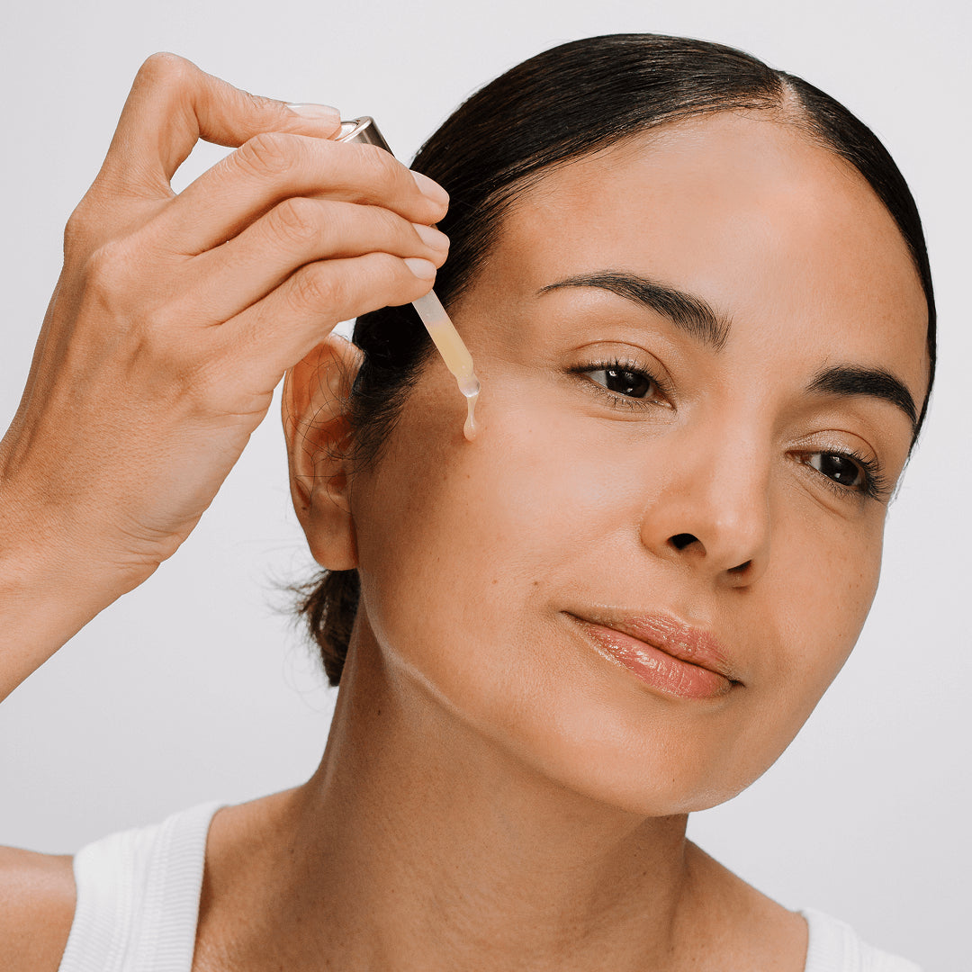 Woman applying a CellLift Serum skincare product to her face with a dropper.