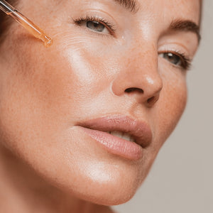 Close-up of a woman's face with a dropper applying CellLift Serum to her skin.