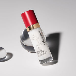 Skincare bottle of cellular eye contour cream with red cap and white label on a gray background