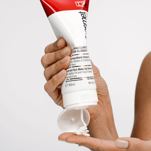 Hand holding a tube of Gentle Cream Cleanser makeup remover with a white background