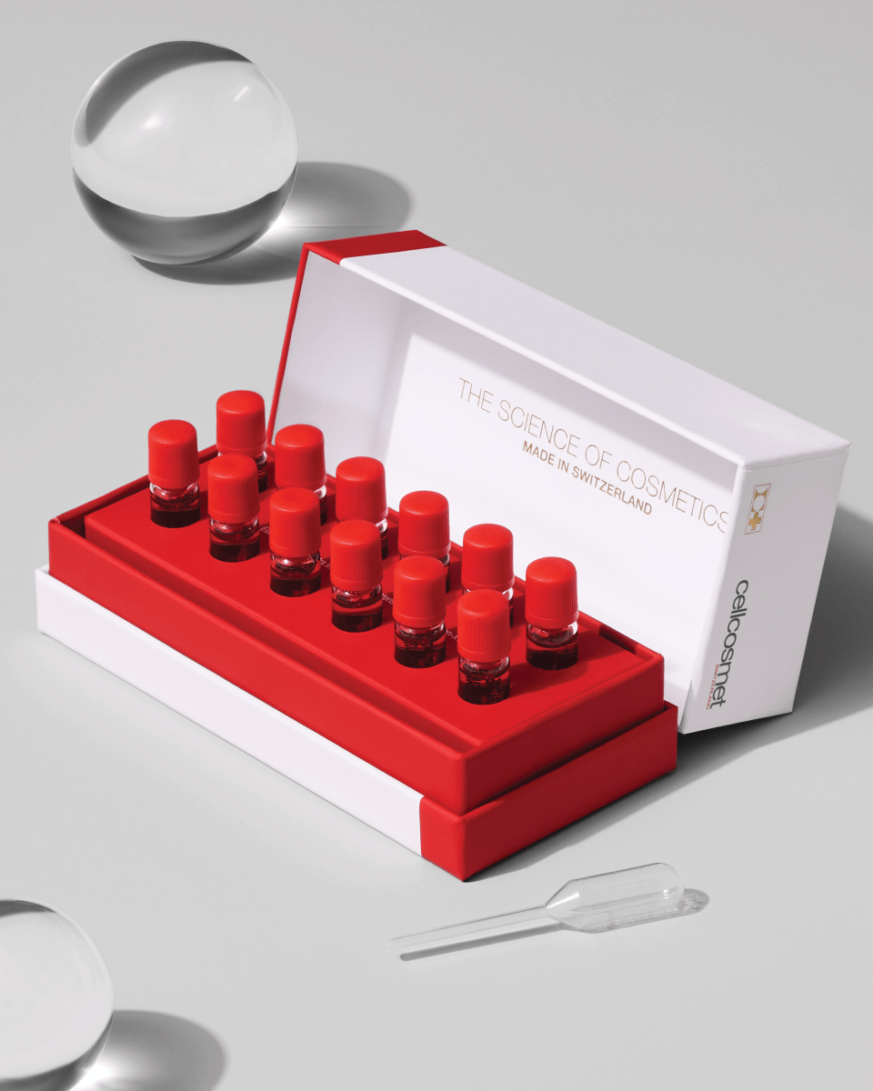 Set of red cosmetic bottles with a white box on a gray background