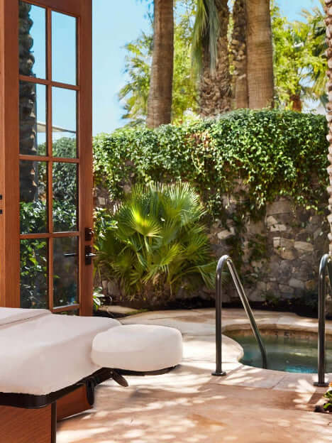Outdoor patio area with a pool, lounge chairs, and palm trees.